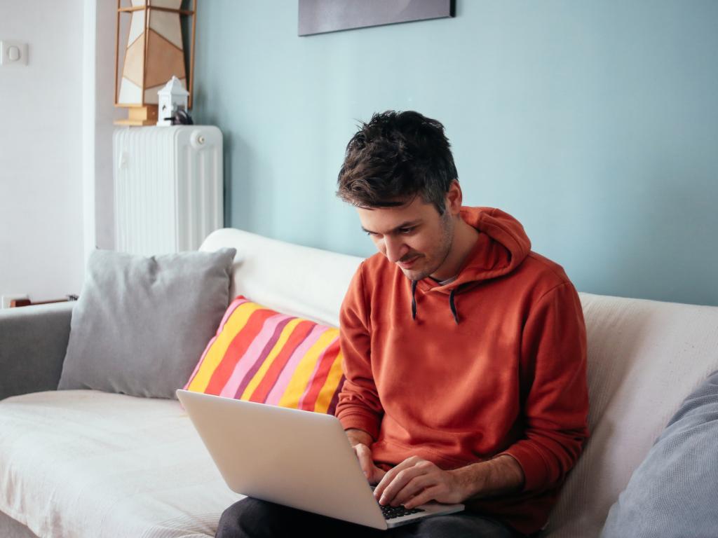 Person sitting on bed with laptop L