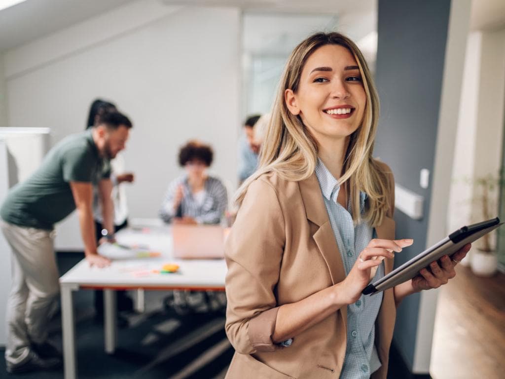 En kvinne i dress holder et nettbrett og ser fokusert og engasjert ut i en profesjonell setting