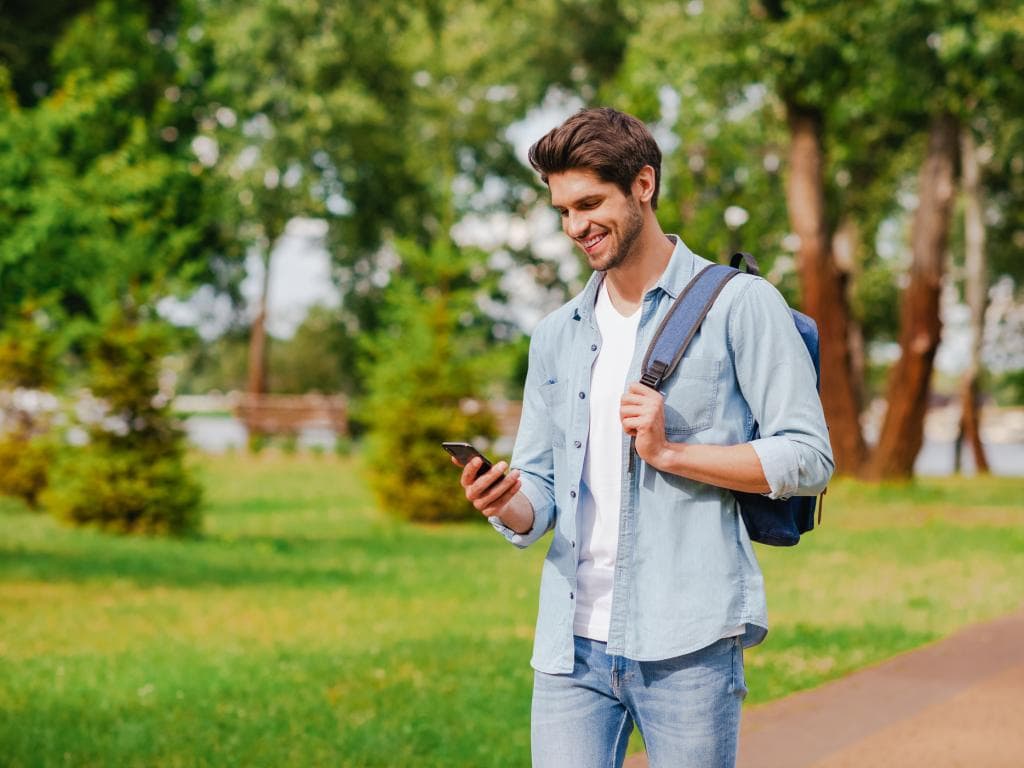 Person in park looking at phone smiling L 0